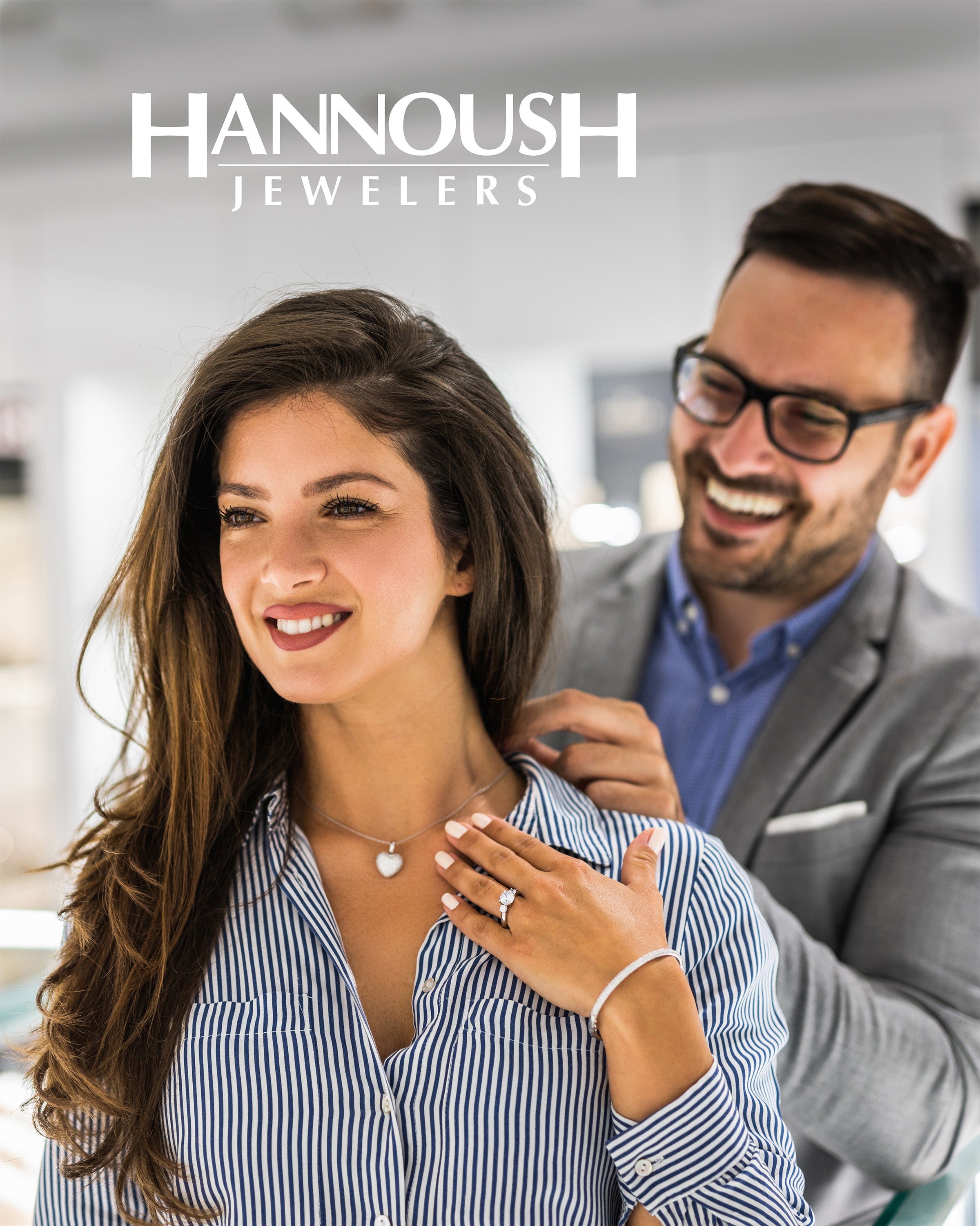Man helps woman put on heart-shaped diamond necklace in jewelry store setting