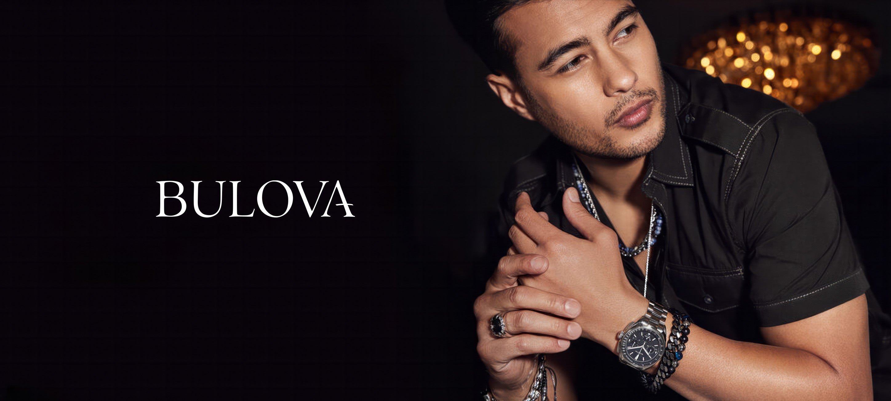 Man wearing Bulova men's watch and jewelry, posing in elegant indoor setting
