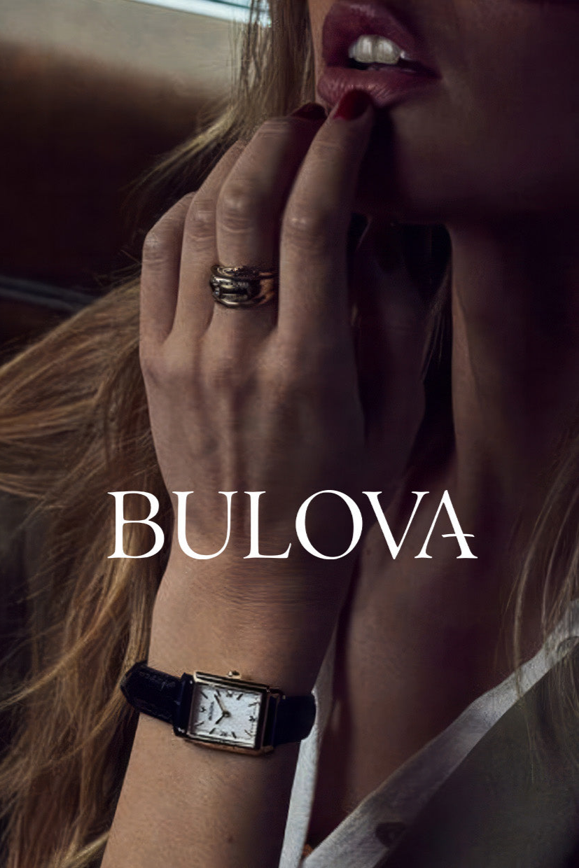 Woman wearing gold rectangular Bulova watch with black leather strap and gold rings