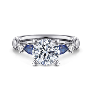 Platinum ring with round diamond center, pear-shaped blue sapphires, and small accent diamonds