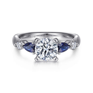 White gold ring with round diamond center, blue sapphire accents, side diamonds