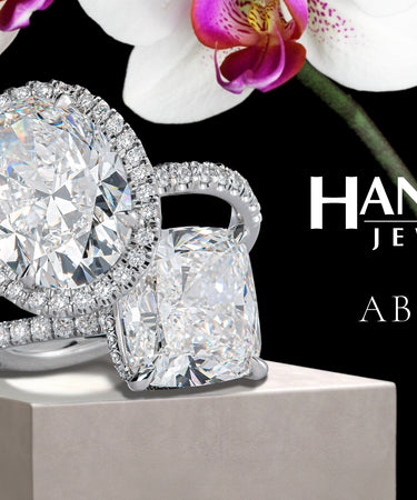 Diamond engagement rings on display with white orchids on black background