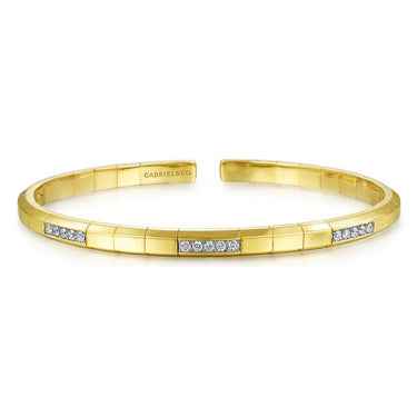 Yellow gold cuff bracelet with diamond accents on a white background
