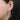 Close-up of a woman's ear wearing a large oval diamond hoop earring