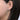 Close-up of a woman's ear wearing a large oval diamond hoop earring