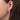 Close-up of a woman's ear wearing a round diamond drop earring with pavé accents