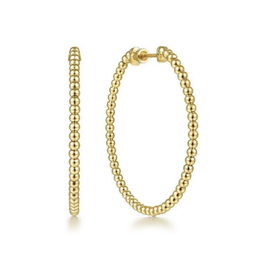 Gold beaded hoop earrings with polished ball detailing on white background
