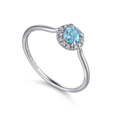 White gold ring with round blue gemstone center, halo of diamonds, elegant thin band