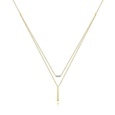 Layered gold necklace with a diamond bar pendant and beaded drop accent on white background