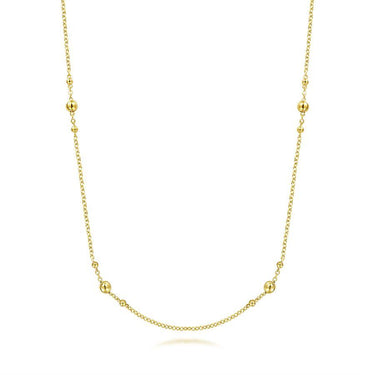 Delicate yellow gold station necklace with polished bead accents on a fine chain