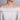 Woman wearing a long gold bead station necklace with off-shoulder white dress