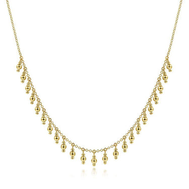 Delicate gold necklace with multiple small dangling bead accents on a fine chain
